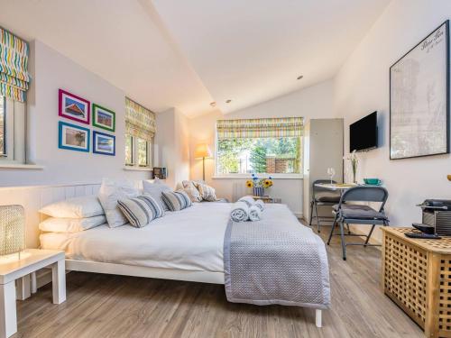 a bedroom with a large white bed and a desk at Pass the Keys Delightful Studio in West Ashling in Chichester