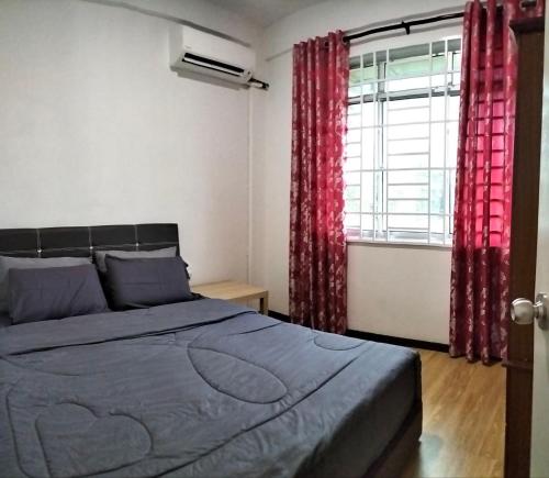 a bedroom with a bed and a window with red curtains at Homestay @Seri Sindang Guesthouse in Kota Samarahan