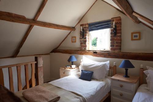 1 dormitorio en el ático con cama y ventana en Badger Cottage at Alde Garden en Saxmundham