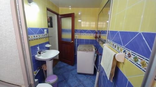 Elegante Apartamento en La Paz في لاباز: حمام ازرق واصفر مع حوض ومرحاض