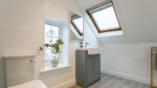 a bathroom with a sink and a toilet and windows at Ty Draw in Abersoch