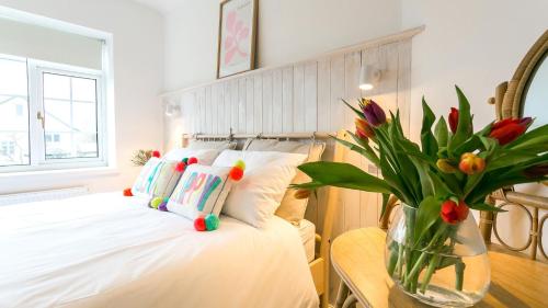 a bedroom with a bed with a vase of flowers at Ty Draw in Abersoch
