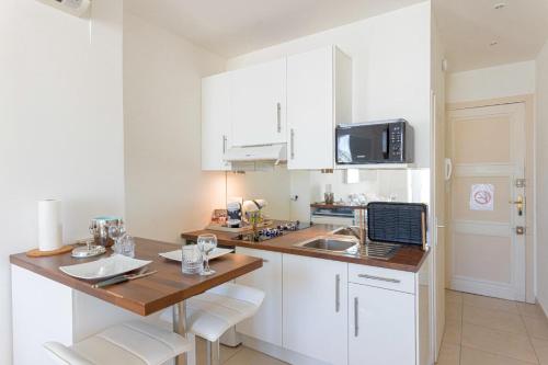 une cuisine avec des armoires blanches et un comptoir en bois dans l'établissement Croisette Beach & Palace, à Cannes