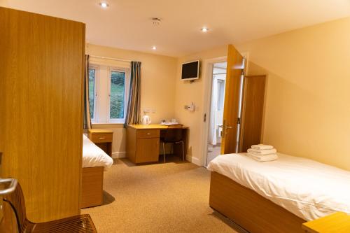 a hotel room with two beds and a desk at Cliff College in Curbar