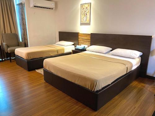 una habitación de hotel con 2 camas y una silla en Ain Studio Apartment, en Kota Bharu