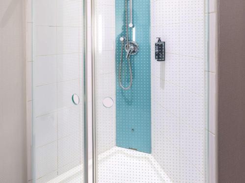a shower with a glass door with a blue shower at ibis Saint Quentin Basilique in Saint-Quentin