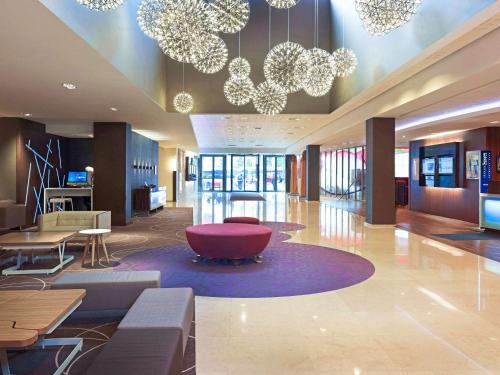 eine Lobby mit Stühlen, Tischen und Kronleuchtern in der Unterkunft Novotel Warszawa Centrum in Warschau