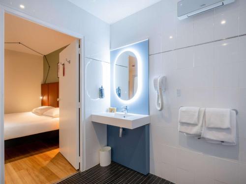 a bathroom with a sink and a mirror and a bed at ibis Paris Père Lachaise in Paris