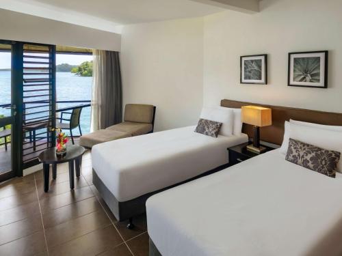 スバにあるノボテル スバ ラミ ベイのベッド2台とバルコニーが備わるホテルルームです。