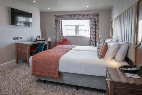 a hotel room with a large bed and a desk at voco The Clifton Folkestone by IHG in Folkestone