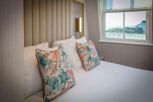 a bedroom with a bed with two pillows and a window at voco The Clifton Folkestone by IHG in Folkestone