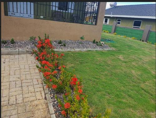 a garden with red flowers in front of a building at Gil- Manor in Falmouth