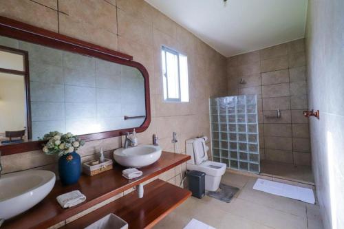 een badkamer met een wastafel, een toilet en een spiegel bij Zuhri Villas Diani in Diani Beach