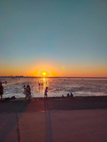 a group of people on the beach at sunset at Apart-Zwergmoewe-im-Moewennest-Tossens in Stick