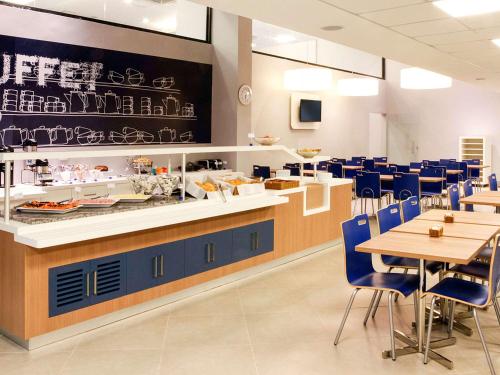 a restaurant with blue chairs and a counter and tables at ibis budget Belo Horizonte Afonso Pena in Belo Horizonte