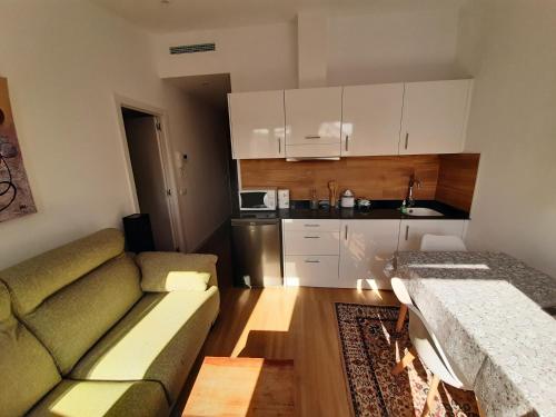 a living room with a couch and a kitchen at Ático Rural en pareja, amigos o familia a la montaña "EL COLMENAR" in Chóvar