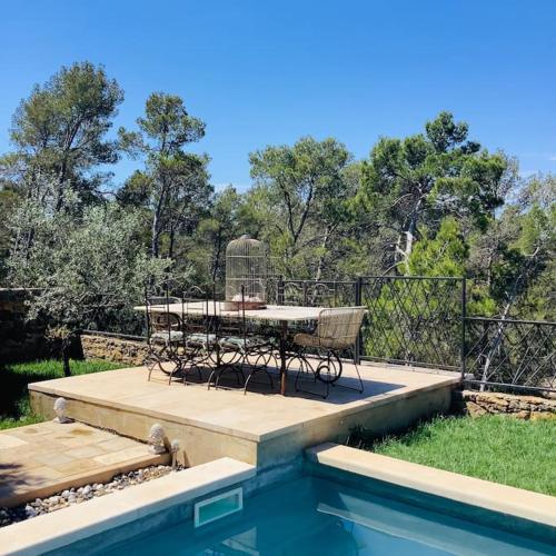 un patio avec une table et des chaises à côté d'une piscine dans l'établissement Villa au coucher de soleil inoubliable sur les collines, à Vidauban