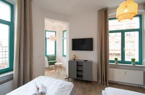 a bedroom with a bed and a tv and windows at Room&Go: Zentral - Balkon - Arbeitsplatz in Halle an der Saale