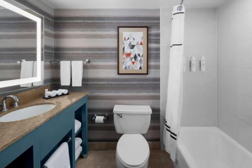 a bathroom with a toilet and a sink and a tub at Embassy Suites by Hilton Phoenix Biltmore in Phoenix