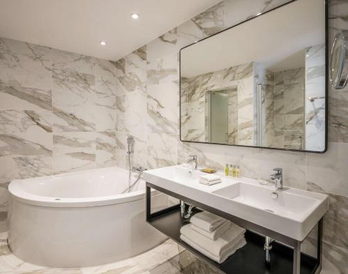 a bathroom with a sink and a tub and a mirror at Hilton Brussels Grand Place in Brussels