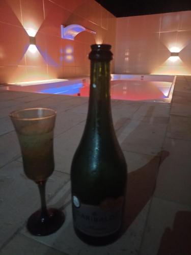 eine Flasche und ein Glas auf einem Tisch mit einem Pool in der Unterkunft Cantinho da Enseadinha in Paulista