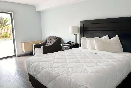 a hotel room with a large white bed and a chair at Travelodge by Wyndham Welland in Welland