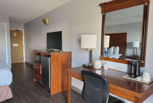 a room with a desk and a bed and a mirror at Travelodge by Wyndham Welland in Welland
