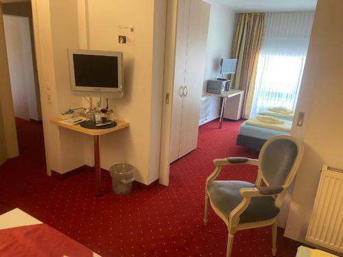 a hotel room with a television and a desk with a chair at Gästehaus Niki in Tauberbischofsheim