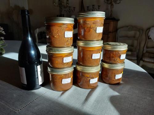 four jars of food on a table with a bottle of wine at Le bourgis in La Chapelle-Montligeon