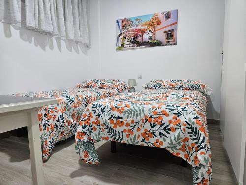 1 dormitorio con 2 camas, mesa y una foto en Apartamentos Atlantis - Yumbo II, en Playa del Inglés