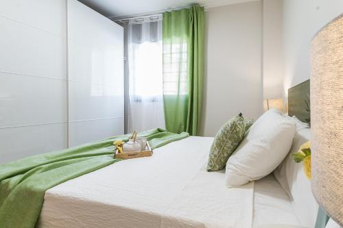 a white bedroom with a bed with a green curtain at Top family apartment by Lofties in Terrassa