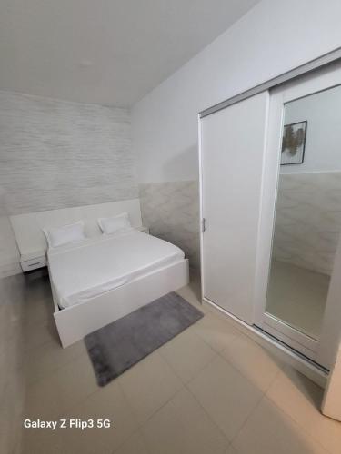 NgorにあるParadis Appartementのベッドと窓のある白い部屋