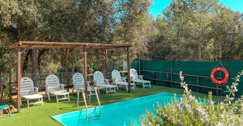 - un groupe de chaises et un kiosque à côté de la piscine dans l'établissement Charming country house with pool and huge garden, à Riudellots de la Creu