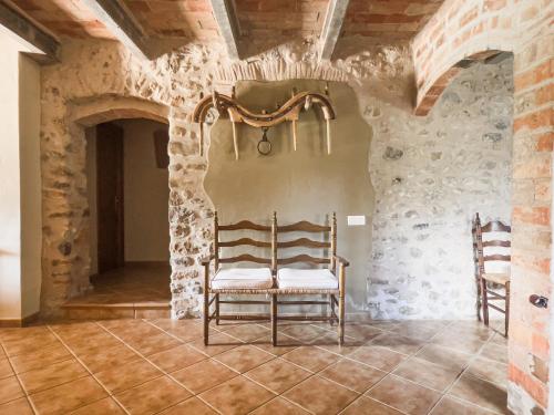 duas cadeiras sentadas numa sala com paredes de pedra em Private country house with pool and barbecue em Girona