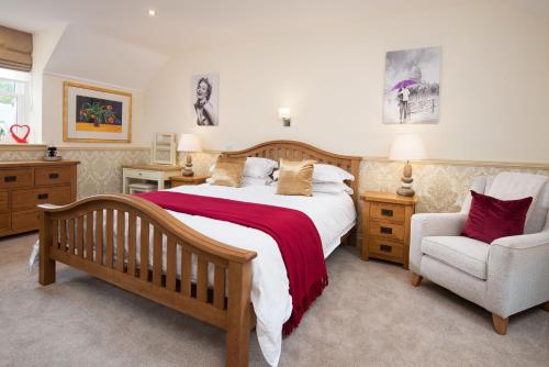 a bedroom with a large bed and a chair at Dryburgh Steading Three in Saint Boswells