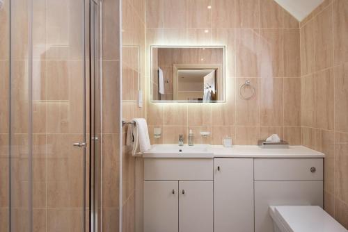 a bathroom with a sink and a shower with a mirror at Dryburgh Steading Three in Saint Boswells