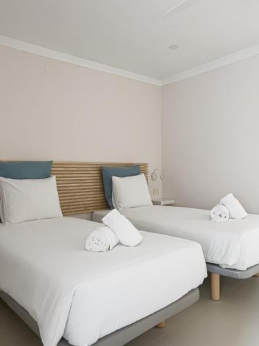 two beds in a hotel room with white sheets at Majordoms - Ca les Cosines 47 in Banyoles