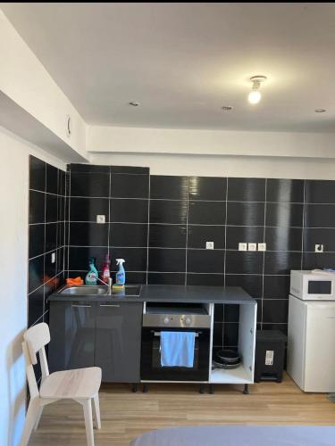 Il comprend une cuisine dotée de murs en carrelage noir et d'une cuisinière. dans l'établissement Studi 400 Vieux Port Opéra, à Marseille