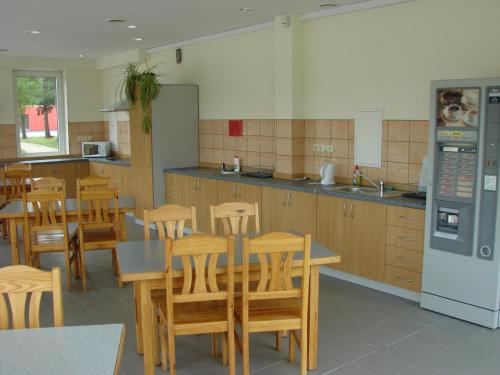 a kitchen with wooden tables and chairs and a refrigerator at Piejūras Kempings in Ventspils