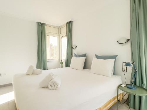 1 dormitorio con 1 cama blanca grande con cortinas verdes en Casa Sarnella, en Port de la Selva