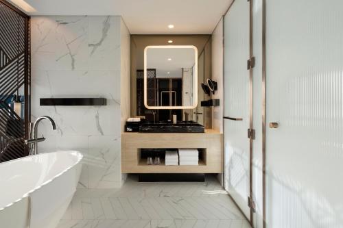 a bathroom with a tub and a sink and a mirror at SO/ Uptown Dubai in Dubai