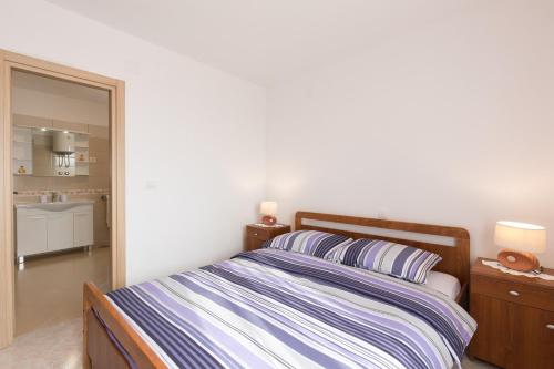 a bedroom with a bed with a striped comforter and a mirror at Apartments Gabi in Punat
