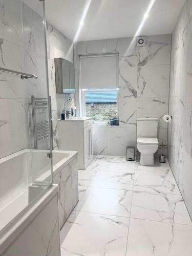 a white bathroom with a toilet and a window at Luxury 3 Bedroom House in Worthing