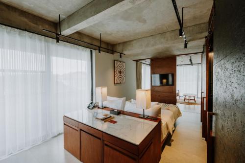 a bedroom with a bed and a desk in a room at The Komu in Canggu