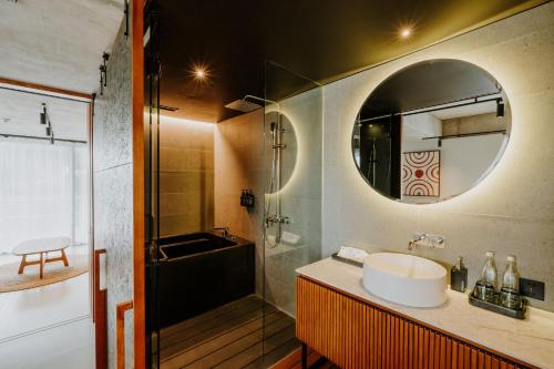 a bathroom with a sink and a tub and a mirror at The Komu in Canggu