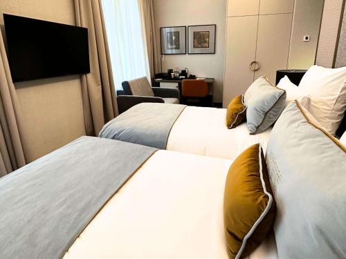 a hotel room with two beds and a television at The Crown Krakow Center - Handwritten Collection ACCOR in Kraków