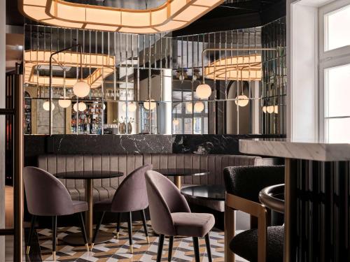 a restaurant with chairs and tables and a bar at The Crown Krakow Center - Handwritten Collection ACCOR in Kraków