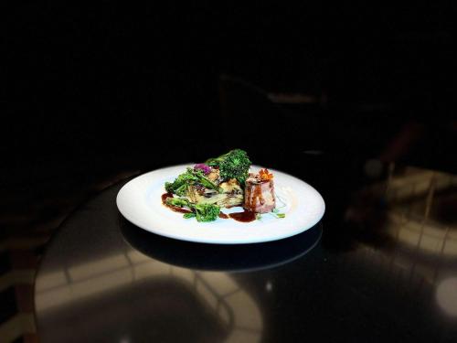 a plate of food with broccoli on a table at The Crown Krakow Center - Handwritten Collection ACCOR in Kraków