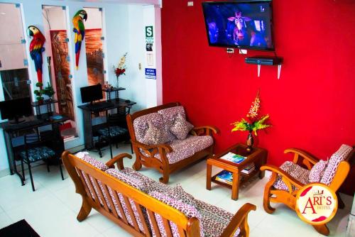 een woonkamer met stoelen en een tv aan een rode muur bij ALLISON HOTEL in Iquitos