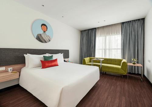 a hotel room with a large white bed and a green chair at Greenpark Hyderabad in Hyderabad